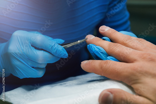 Manicurist cuts a cuticle on a man   s hand with scissors