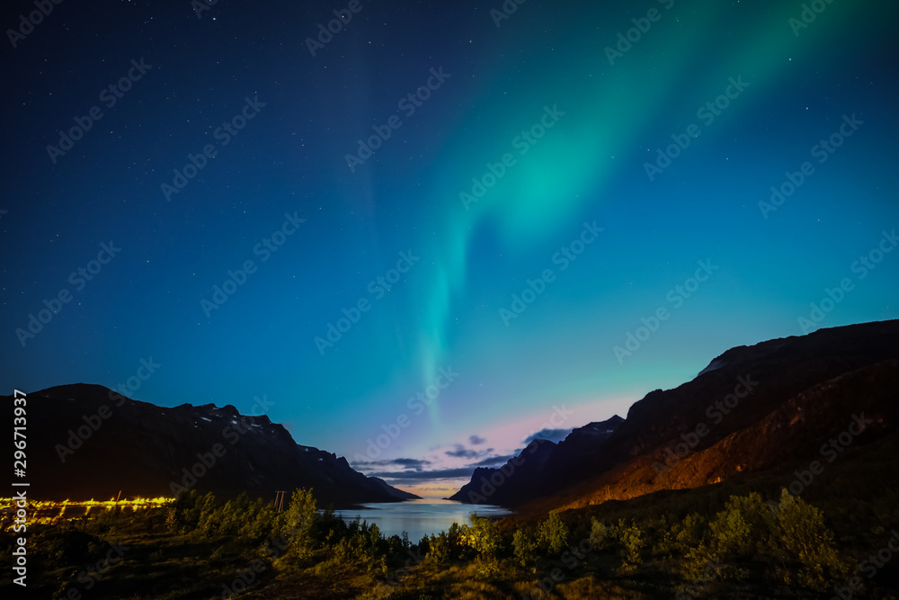 Autumn aurora. Northern lights above fjord and mountains at sunset. multi colored. Ersfjordbotn, Tromso, Norway.