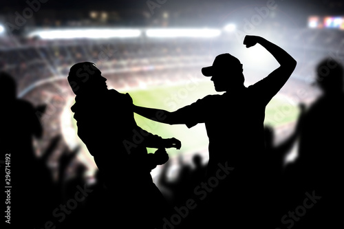 Fight in a football game crowd. Angry man hitting another spectator in soccer match audience. Violent argument between two fans of different teams and clubs. Hooligans and violence in sport event.