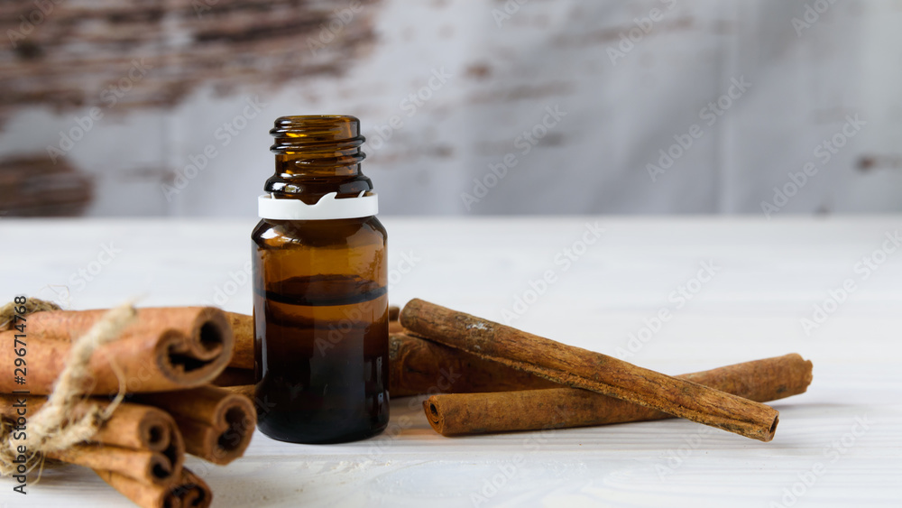 close-up, cinnamon sticks and cinnamon oil on a white wooden background close-up, cinnamon sticks and cinnamon oil on a white wooden background