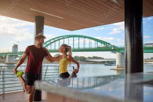 Modern woman and man exercising in urban surroundings near the river.