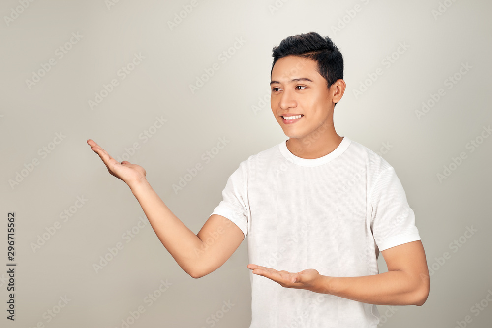 Young handsome man pointing to the side with hand and open palm, presenting ad smiling happy and confident Young handsome man pointing to the side with hand and open palm, presenting ad smiling happy and confident