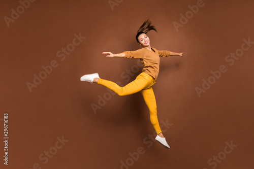 Full length body size photo of cheerful charming fascinating cute nice girl running jumping like ballerina satisfied pleased isolated over brown pastel color background