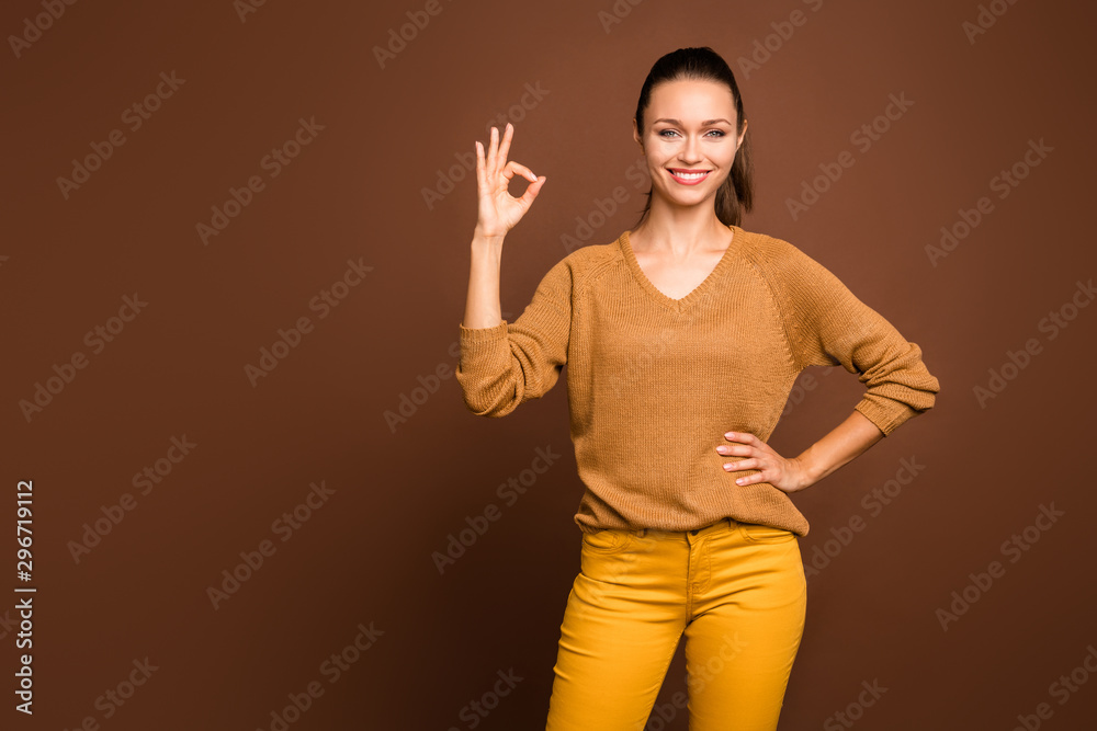 Photo of cheerful confident attractive youngster holding hand on waist showing you ok sign wearing brown sweater isolated over brown color pastel background Photo of cheerful confident attractive youngster holding hand on waist showing you ok sign wearing brown sweater isolated over brown color pastel background