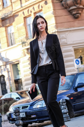 Black haired girl.Business woman in black classic suit.White blouse.Fashion style.Working on tablet.Walk © Yaroslav