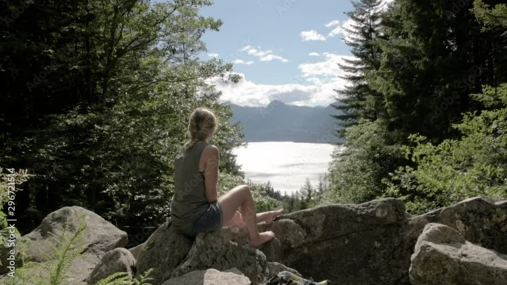 Girl sitting in the forest enjoying a beautiful view of a lake Girl sitting in the forest enjoying a beautiful view of a lake