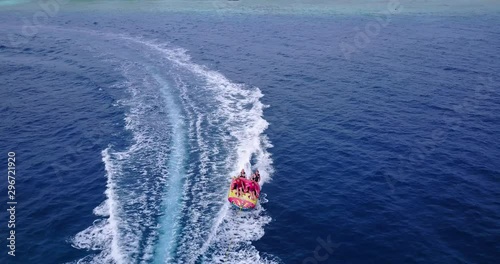 Tourists Enjoying A Ride On A Rented Inflatable, Maafushi Island, Maldives, aerial drone parallax shot, photo