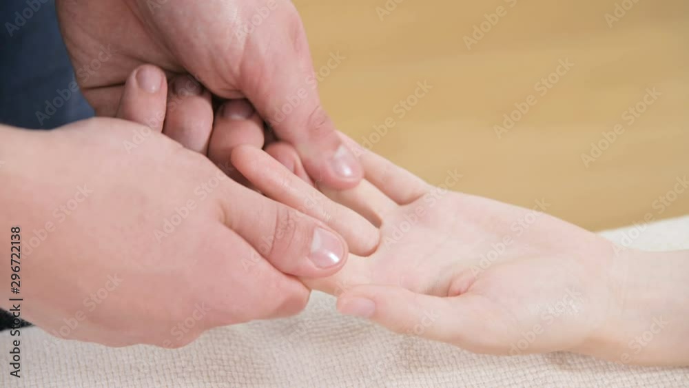 Close-up of a male physiotherapist doing finger and palm massage to a young girl in a massage spa salon. Professional pampering and deep relaxation Close-up of a male physiotherapist doing finger and palm massage to a young girl in a massage spa salon. Professional pampering and deep relaxation