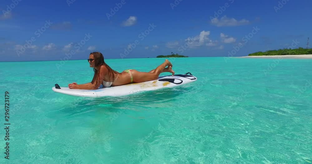 Woman in the ocean on a surfboard sunbathing Woman in the ocean on a surfboard sunbathing