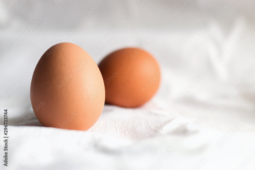 Brown chicken eggs on a light background of cotton fabric, Studio photo, light from the window, selective focus Brown chicken eggs on a light background of cotton fabric, Studio photo, light from the window, selective focus