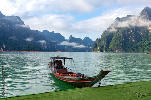 Motor wooden boat in lake with limestone mountain range background © oppdowngalon