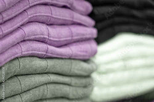 Warm clothing neatly folded on a store shelf. Sweatshirts, sweaters, jumpers, cardigans, hoodies, bobmers with piles on the shelf. Clothes storage. Size range. © Natalya Lys