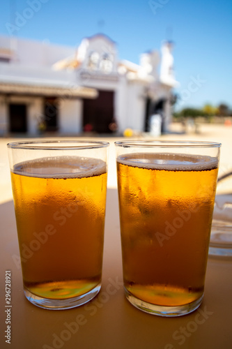 Cold amber color light spanish beer served in glass in outdoor cafe in town on sand, El Rocio in Andalusia, Spain photo