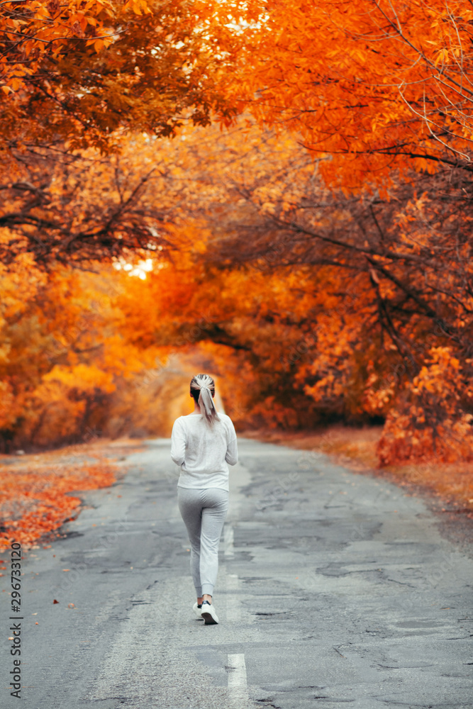 back of young woman in sportswear running distance on asphalt road, girl engaged in sport outdoors on autumn day, concept healthy lifestyle and bodycare back of young woman in sportswear running distance on asphalt road, girl engaged in sport outdoors on autumn day, concept healthy lifestyle and bodycare