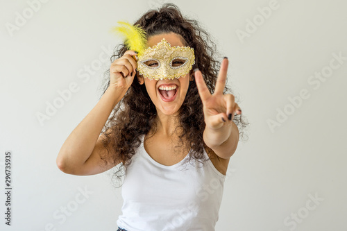 Young woman smiling holding carnival mask on white background photo