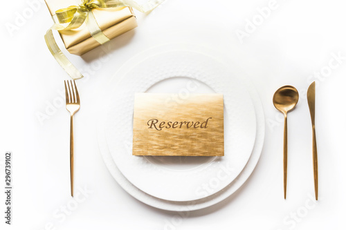 Christmas table setting with golden dishware, silverware and party decorations on white background. Top view. Xmas invitation. Table Reserved.
