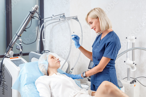 Cosmetology Service. Young woman at beauty clinic lying while doctor holding syringe with hyaluronic acid cheerful