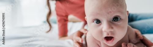 panoramic shot of woman touching baby daughter lying on bed