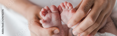 panoramic shot of woman doing massage while touching legs of infant baby