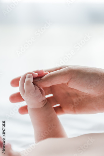 cropped view of woman doing massage while touching hand of infant baby