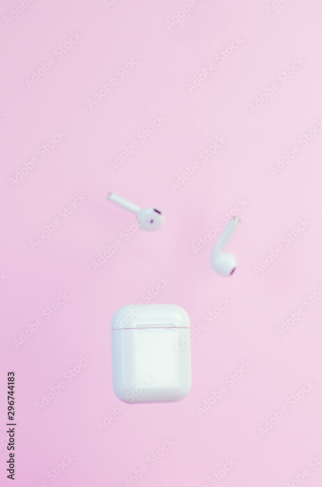Wireless white headphones with a case on a pink background. New technologies. Trend. Wireless white headphones with a case on a pink background. New technologies. Trend.