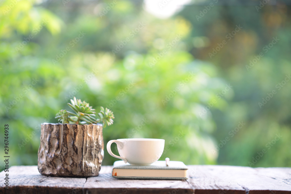 white cup with book and small cactus in wooden pot on wooden table white cup with book and small cactus in wooden pot on wooden table