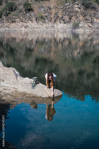 Woman in the river touching reflection
