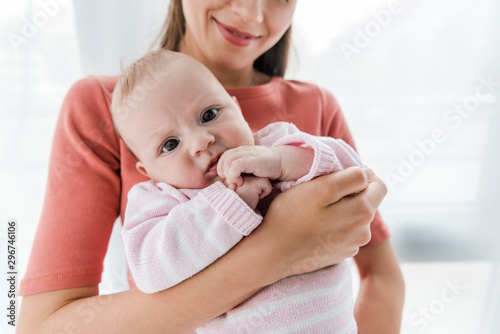 cropped view of happy woman holding in arms adorable infant daughter
