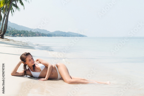 Young woman lying on a tropical white sand beach