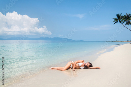 Young woman lying on a tropical white sand beach