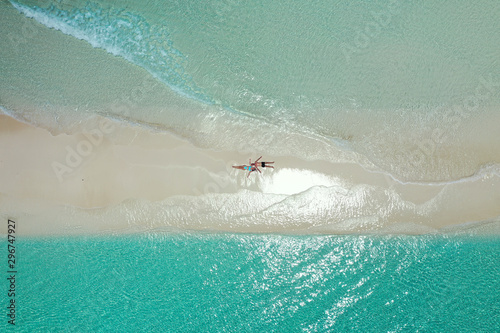 romantic couple stretched on the white sand of a maldivian beach from aerial view