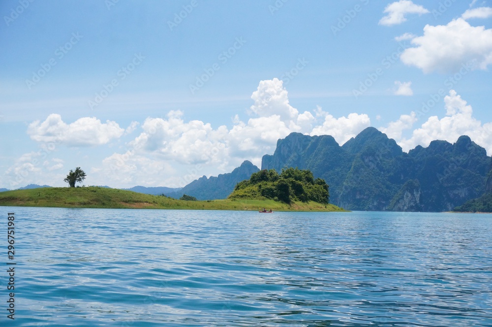 Beautiful view from Ratchaprapa dam in Thailand. Beautiful landscape view with blue water, blue clouds sky and mountains at the background. Tourists in the boat are enjoying the view