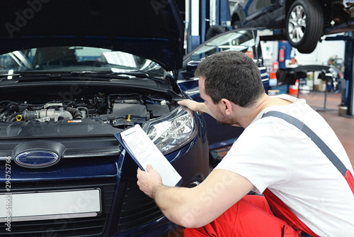 Automechaniker kontrolliert Scheinwerfer - Lichtanlage beim KFZ in der Werkstatt // Car mechanic checks headlights - lighting system in the workshop of a motor vehicle