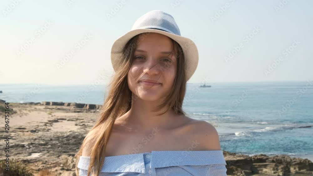 Portrait of Smiling cute teenage girl in hat. Concept israeli people, mediterranean sea coastline in background. Slow motion x2 Portrait of Smiling cute teenage girl in hat. Concept israeli people, mediterranean sea coastline in background. Slow motion x2
