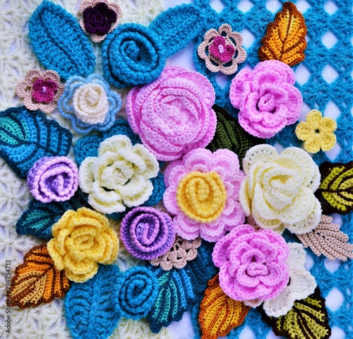 Multicolored crocheted flowers and leaves on crocheted background.