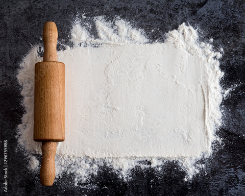 Fotografia Rolling pin and white flour on a dark background
