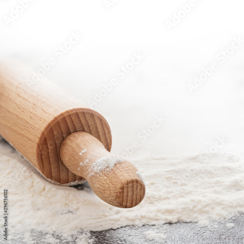 Rolling pin and white flour on background