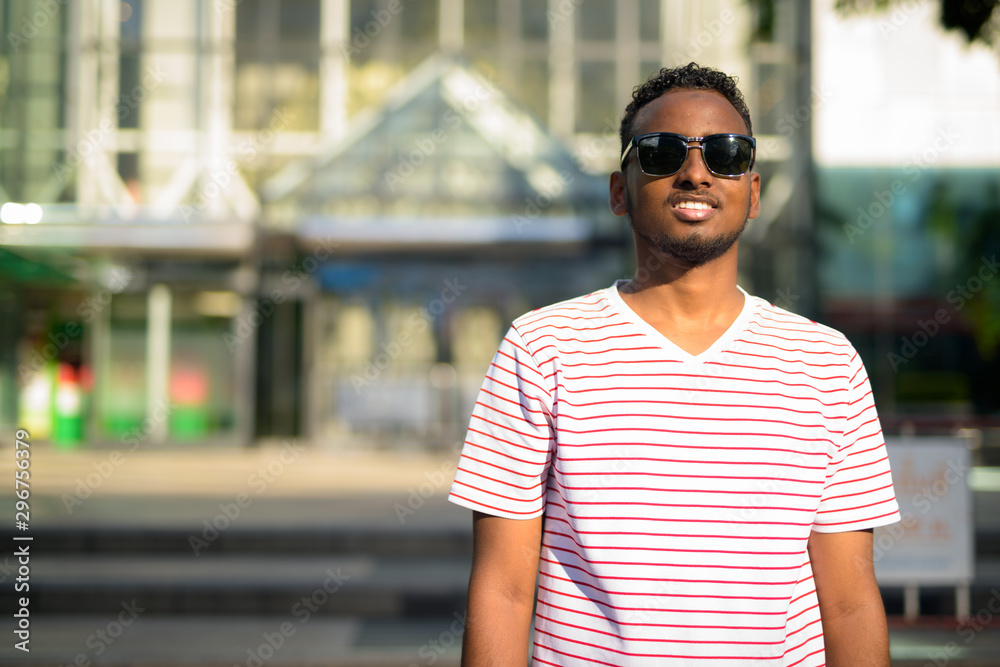 Happy young African bearded man with Afro hair in city Happy young African bearded man with Afro hair in city