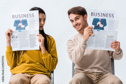 woman looking at happy man holding business newspaper isolated on white