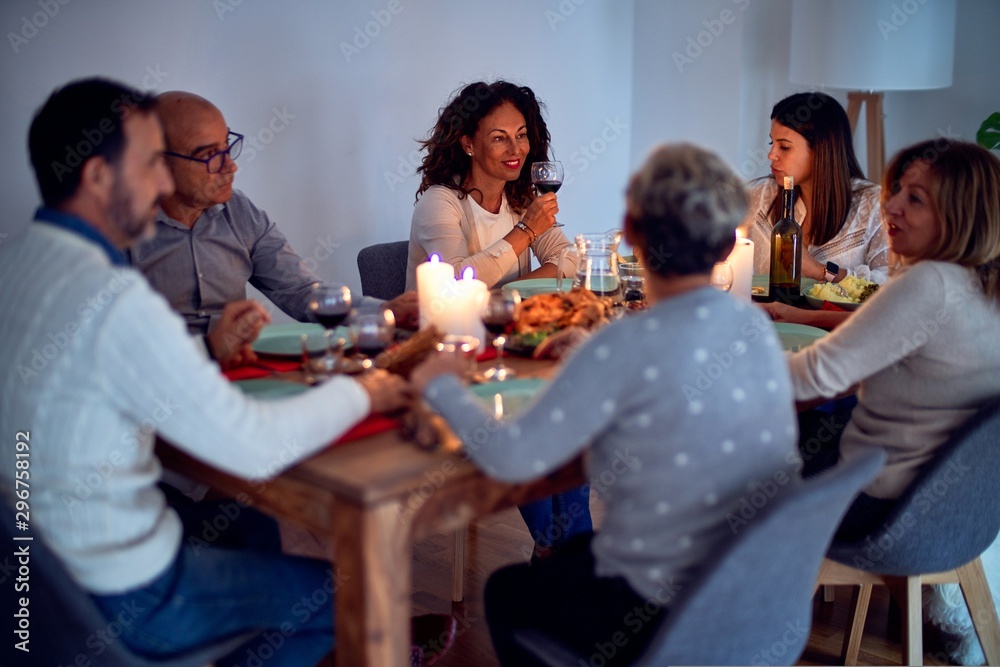 Family and friends dining at home celebrating christmas eve with traditional food and decoration, all sitting on the table together