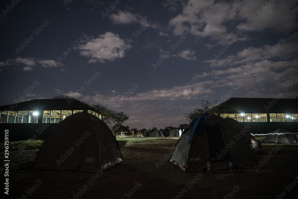 Camping overnight in tents in savanna Serengeti camp during safari expedition. Amazing stars over tents