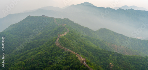 Panoramic view of Great Wall of China with a green trees and mist in a background. photo