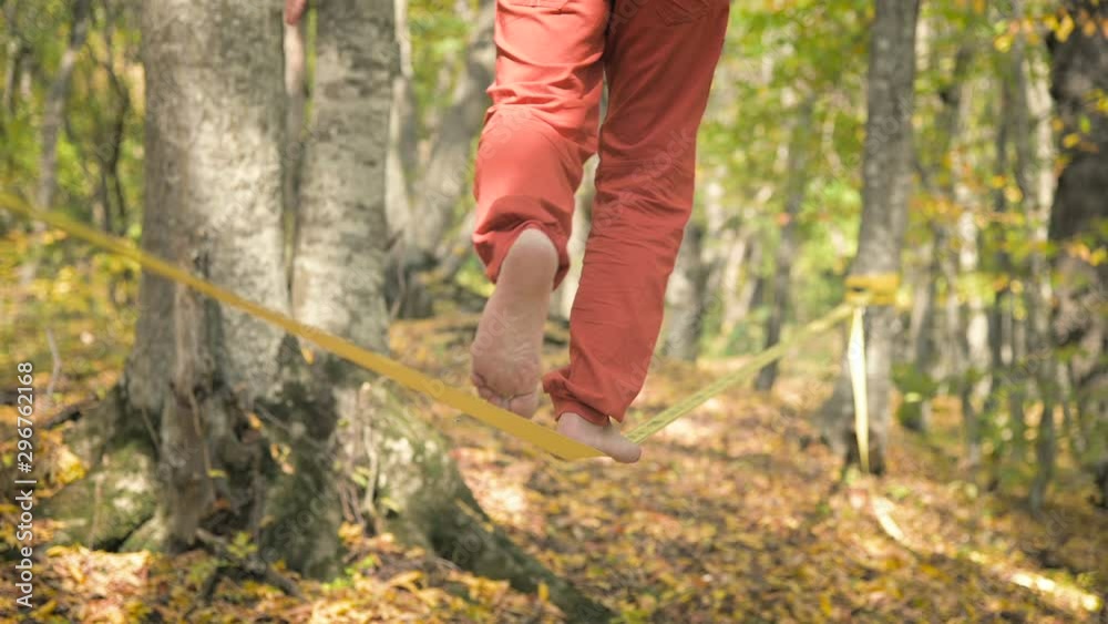 A Slack man aged with a beard in sportswear walks balancing on the slackline. The concept of sports activity at the age of 50. Athlete's foot closeup