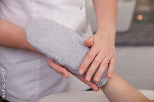 Fototapeta Female hand in beauty spa salon with paraffin wax in glove