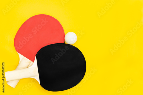 two ping pong table tennis rackets on a bright yellow background.
