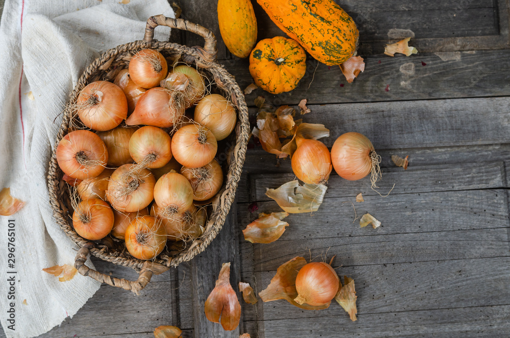 Obraz premium Onions in a basket - from above in a rustic vintage table with orange pumpkins and textured napkin - autumn background image