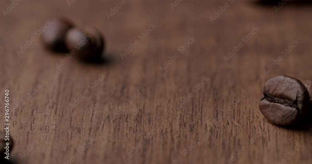 detail shot of a few roasted coffee beans getting scatterd on a wooden table and afterwards wiped away by a caucasian hand. Loopable shot. detail shot of a few roasted coffee beans getting scatterd on a wooden table and afterwards wiped away by a caucasian hand. Loopable shot.