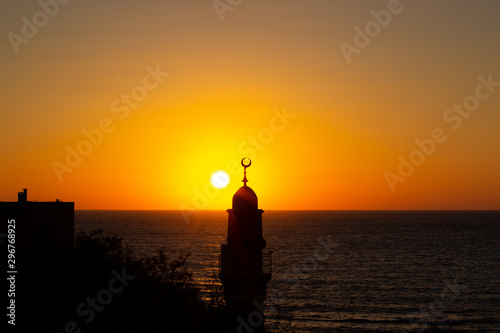 religion country side sea waterfront scenic view of minaret tower silhouette on vivid orange sunset lighting background 