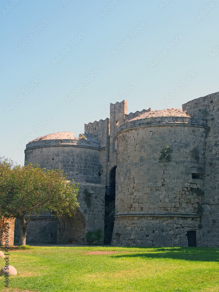 the amboise gate in the medieval walls of the old city in rhodes town surrounded by grass and trees