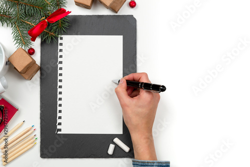 Christmas letter writing on paper on white desk with decorations. Wish list writing. 2020 resolution list photo